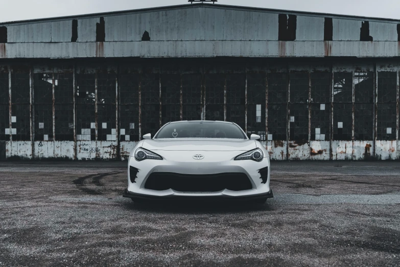 white sports car parked in front of large metal building