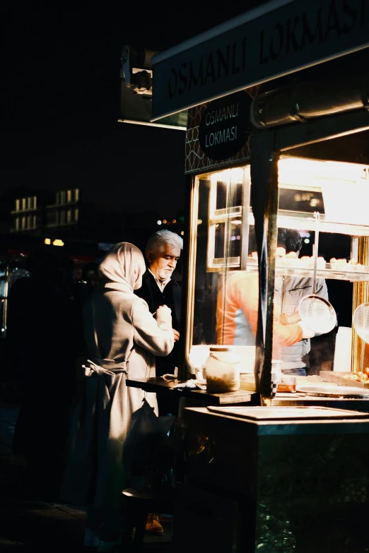 two people standing in front of a food cart