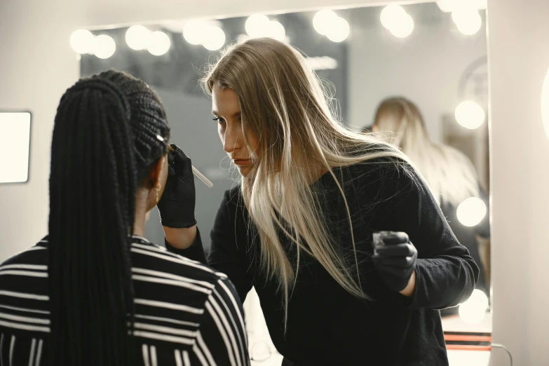 two woman are having their hair done in a mirror