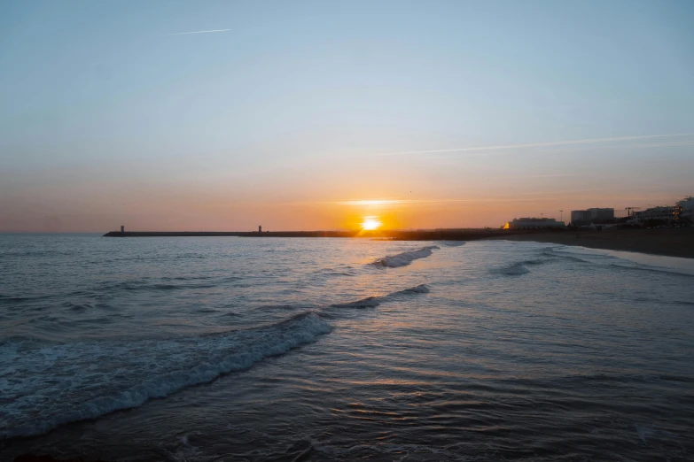 the sun is setting over the ocean with small waves