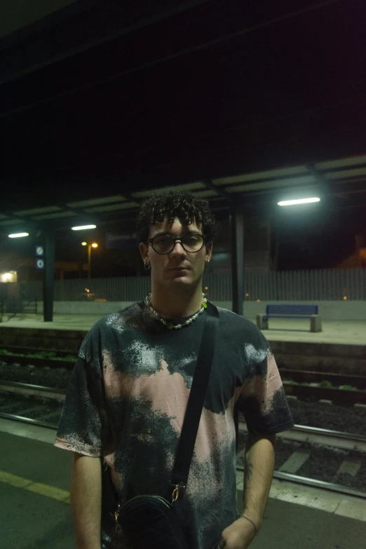 the man stands on the train platform with his hands in his pockets