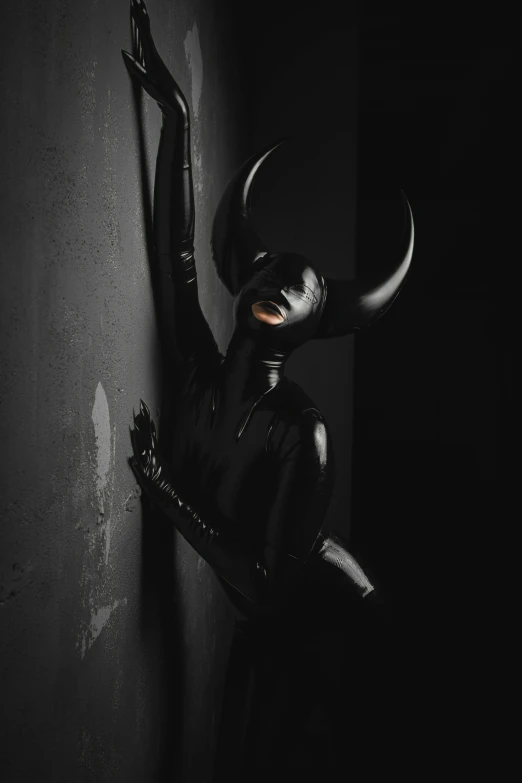 a woman in catwoman outfit, leaning against a wall