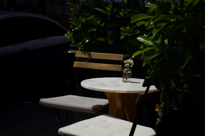 a chair next to a small table with a vase of flowers on top of it