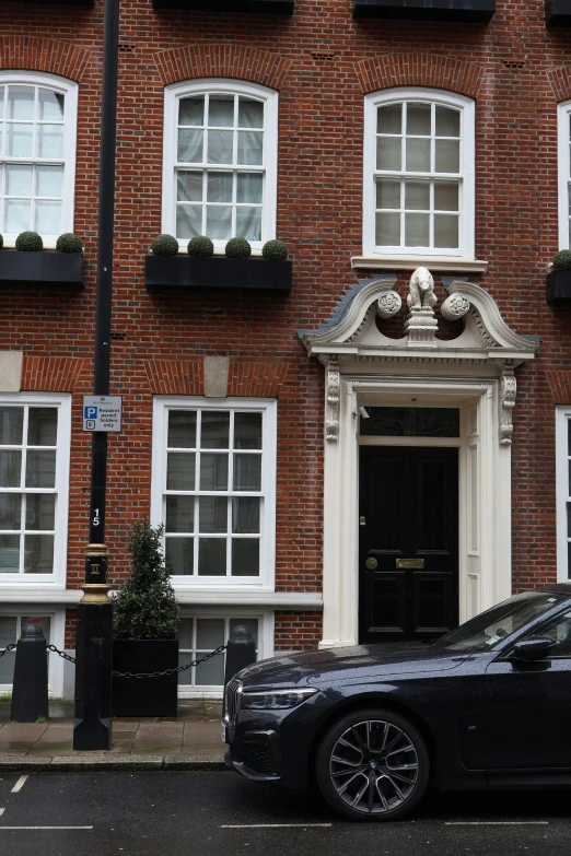 a black car is parked in front of a brick building