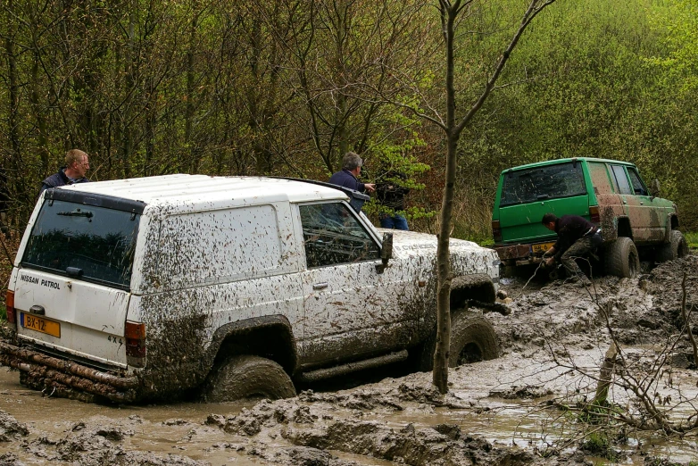 a couple of cars driving through some muddy roads