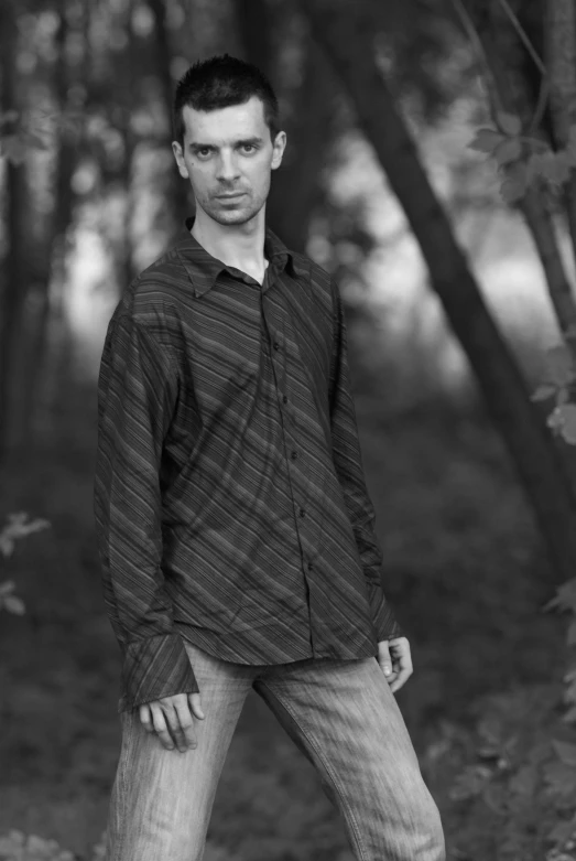 a young man wearing a long shirt and jeans posing for a pograph
