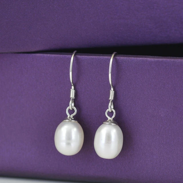 pair of pearls in silver earrings against a purple background