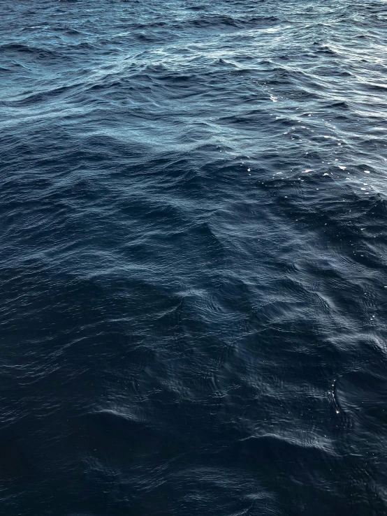 a blue sea is shown with sunlight reflected on the water