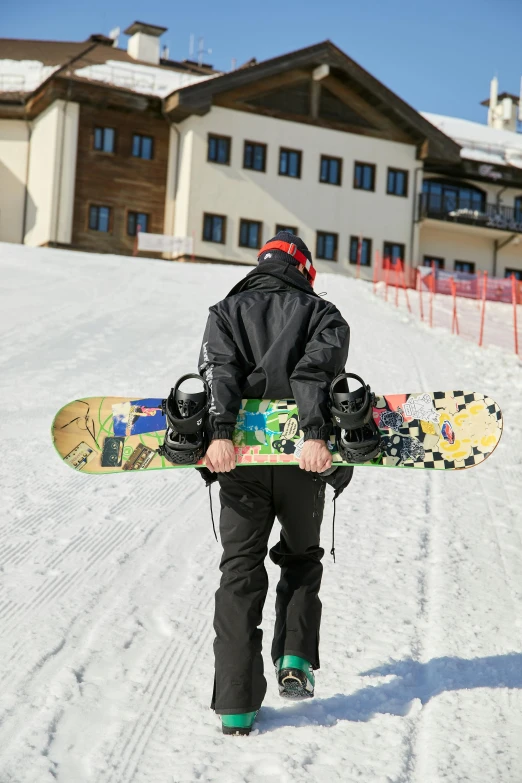 a man carrying a snowboard down a snowy slope