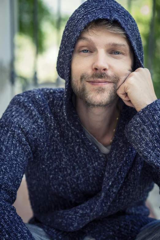 a man with a hooded sweater on posing for a picture