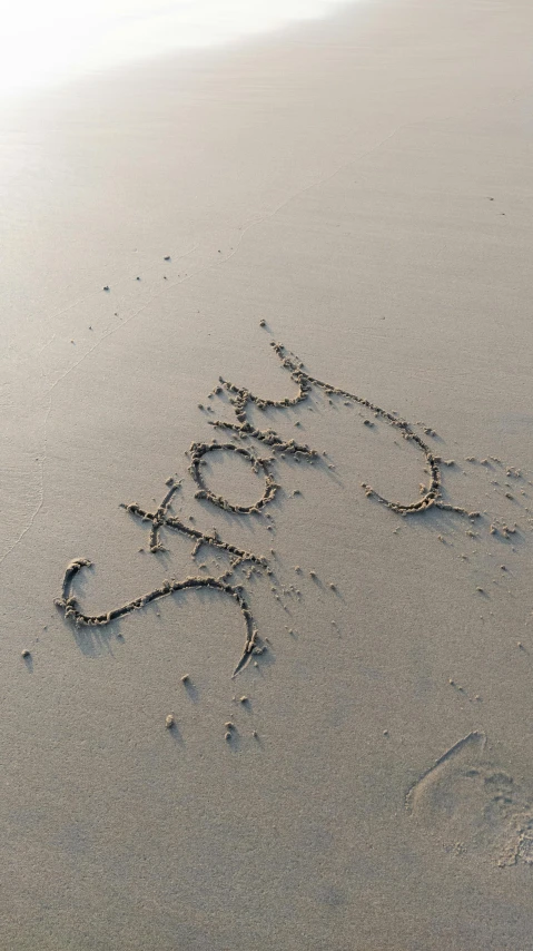 some sand writing in the sand and some water