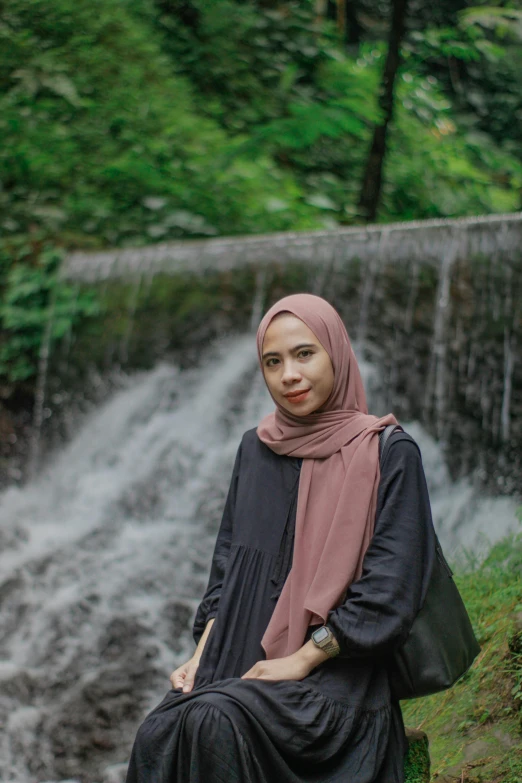 a woman sitting in front of a waterfall