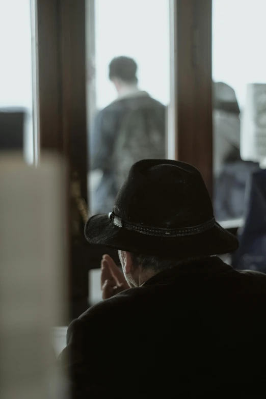 a man is sitting in front of windows in a hat