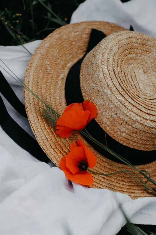 a straw hat with two small orange flowers lying on it