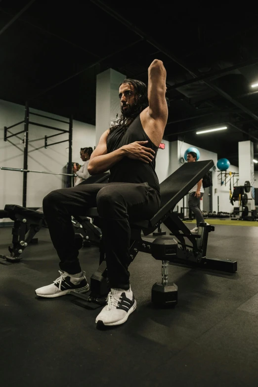 man seated on a bench flexing his arm