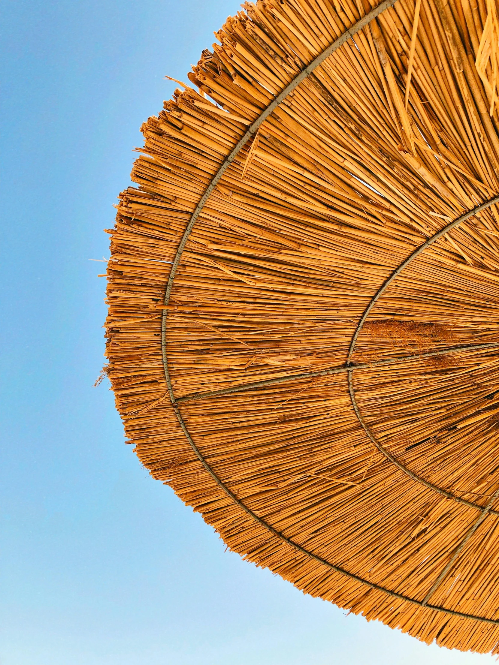 the top of a large straw umbrella on a sunny day
