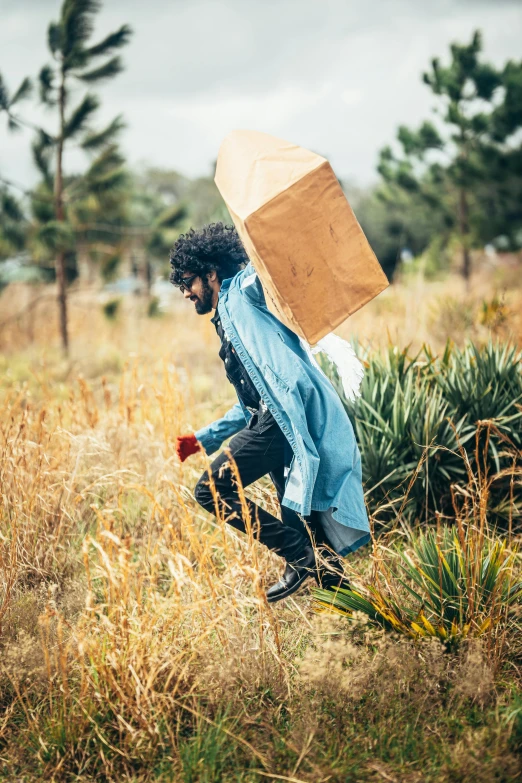 man in a field carrying an umbrella over his head