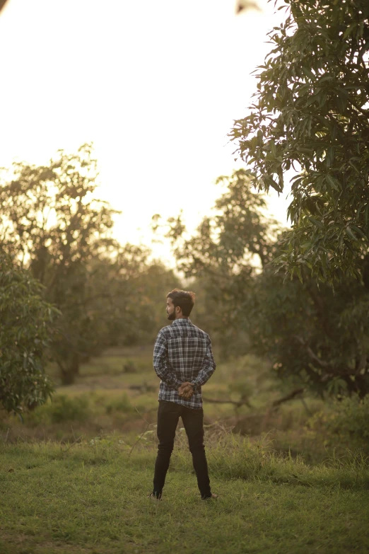 a young man standing in an open field looking to his left