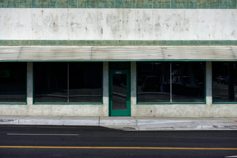 an empty road lined with store windows and closed shutters