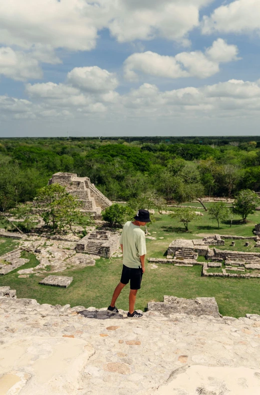 a man stands on the edge of a cliff near an ancient village