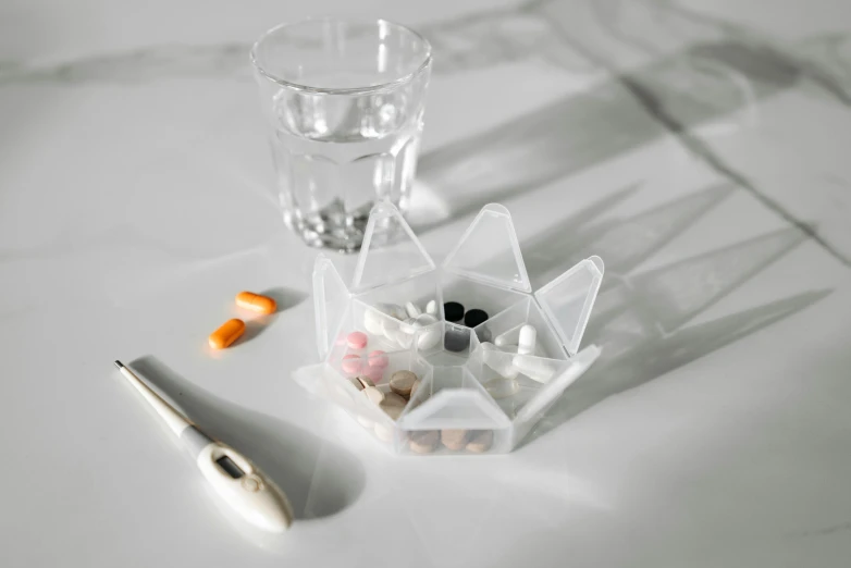 a clear glass sits next to pill bottles and an empty glass