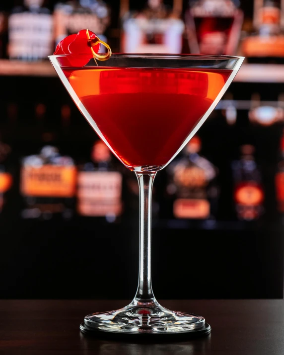 the bright red alcoholic cocktail is in a coupe glass