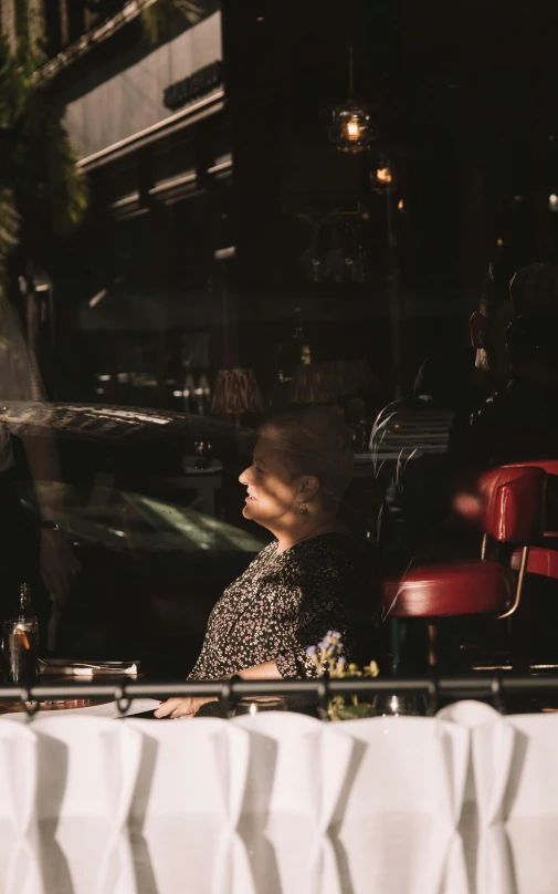 a woman is sitting outside looking out the window