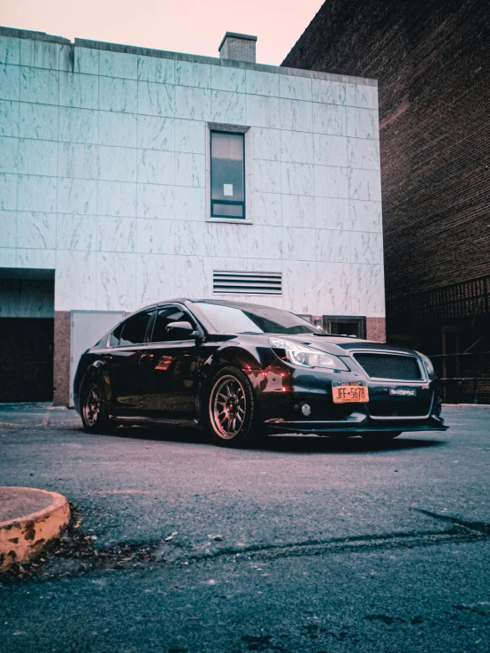 a black car is parked on a paved area near an office building