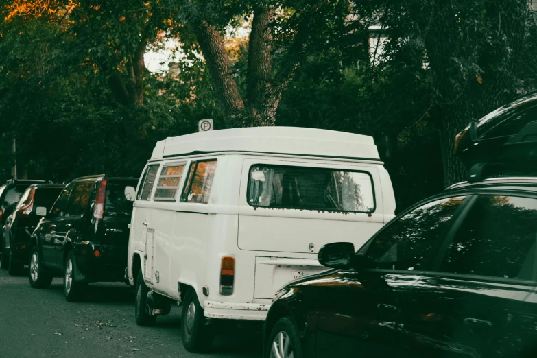 a van is parked on a city street next to parked cars