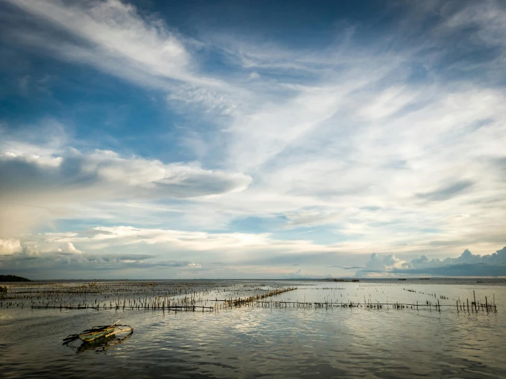 a body of water sitting below a cloudy sky