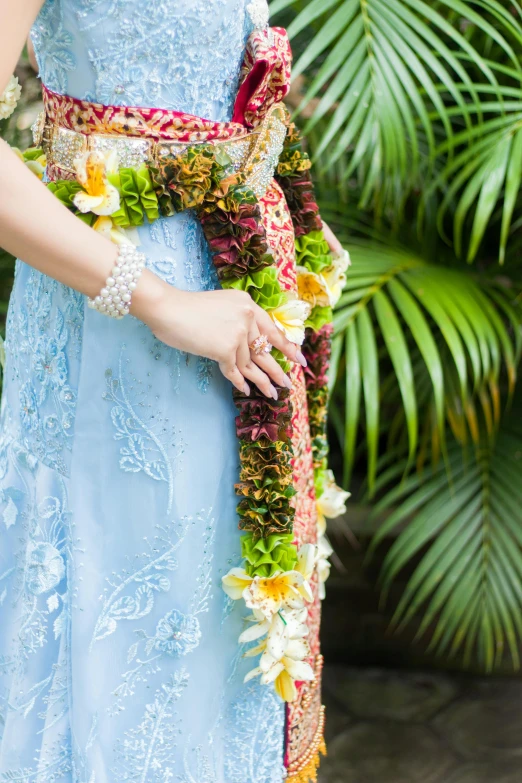 the woman is wearing a blue gown and an intricate hand beaded sash