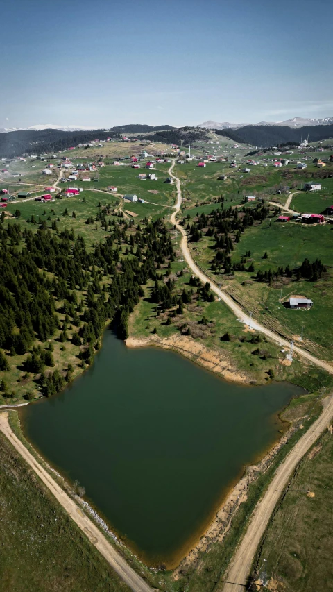 a lake in the middle of a field surrounded by trees