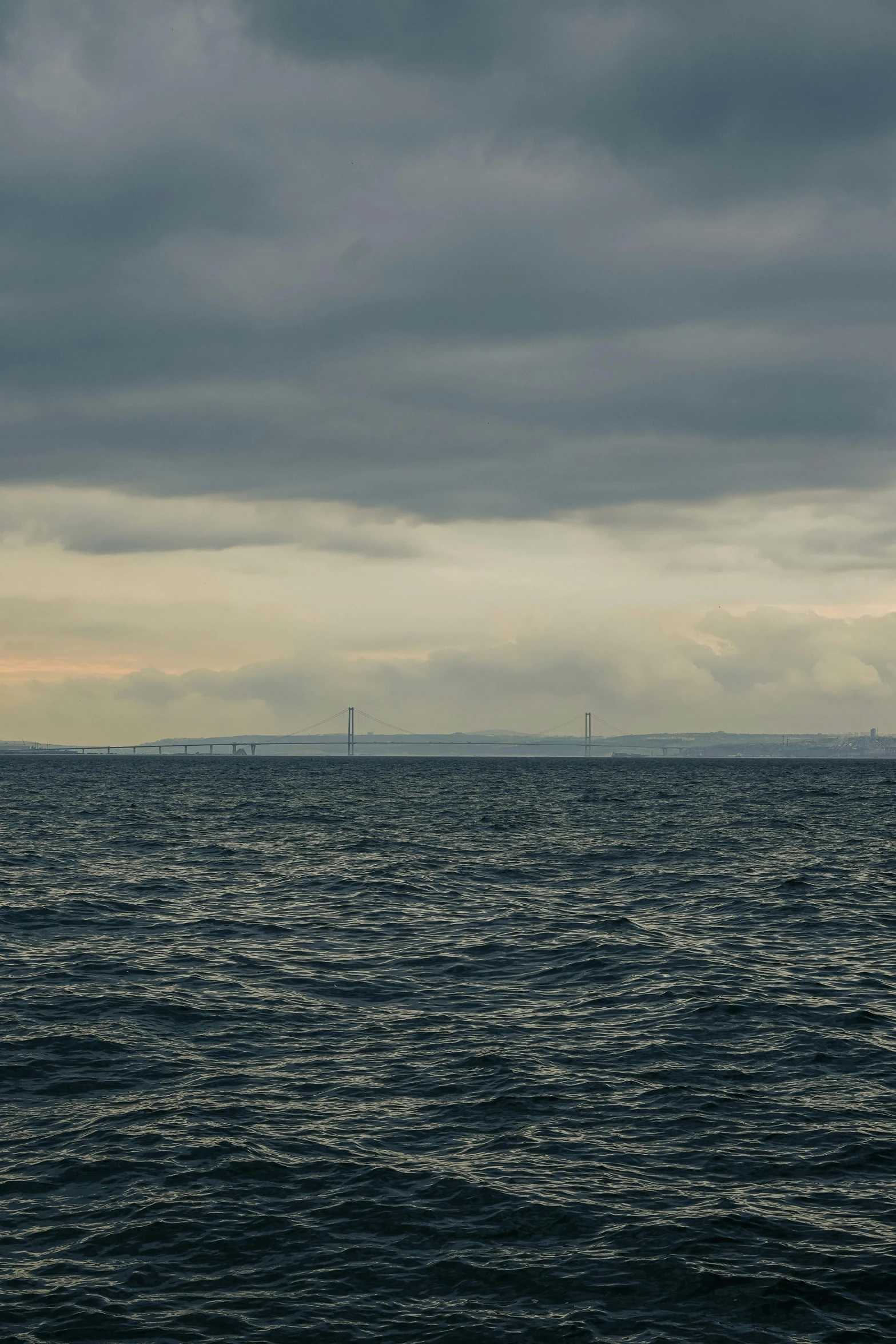 a body of water under a cloudy sky with a lighthouse in the distance