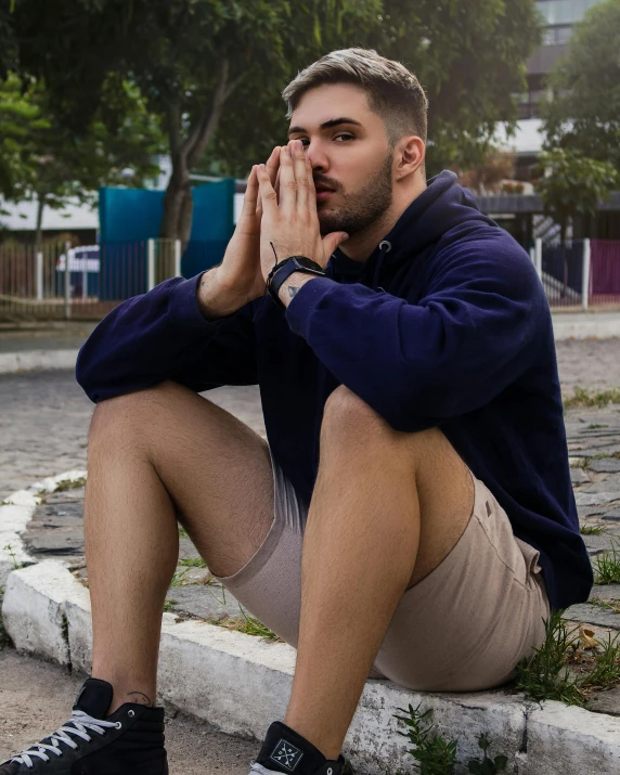 a young man sits on the curb talking on his cell phone