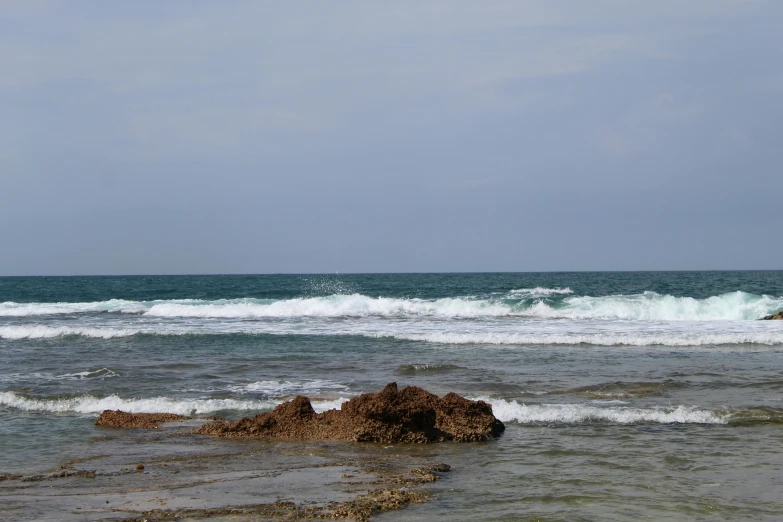 some rocks in water and a surfer riding a surfboard