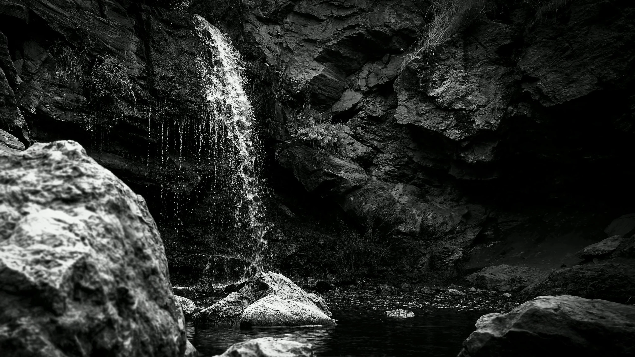 a waterfall flowing over rocks next to a lake