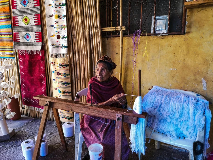 an old woman works with some yarn as she sits on a couch in her living room