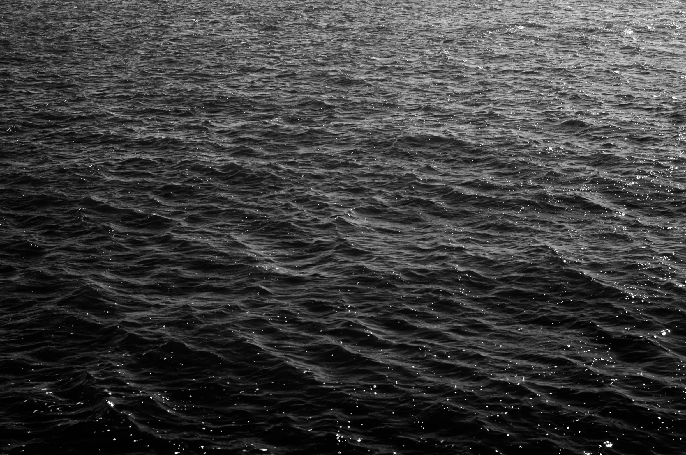 a view of the ocean with waves in black and white