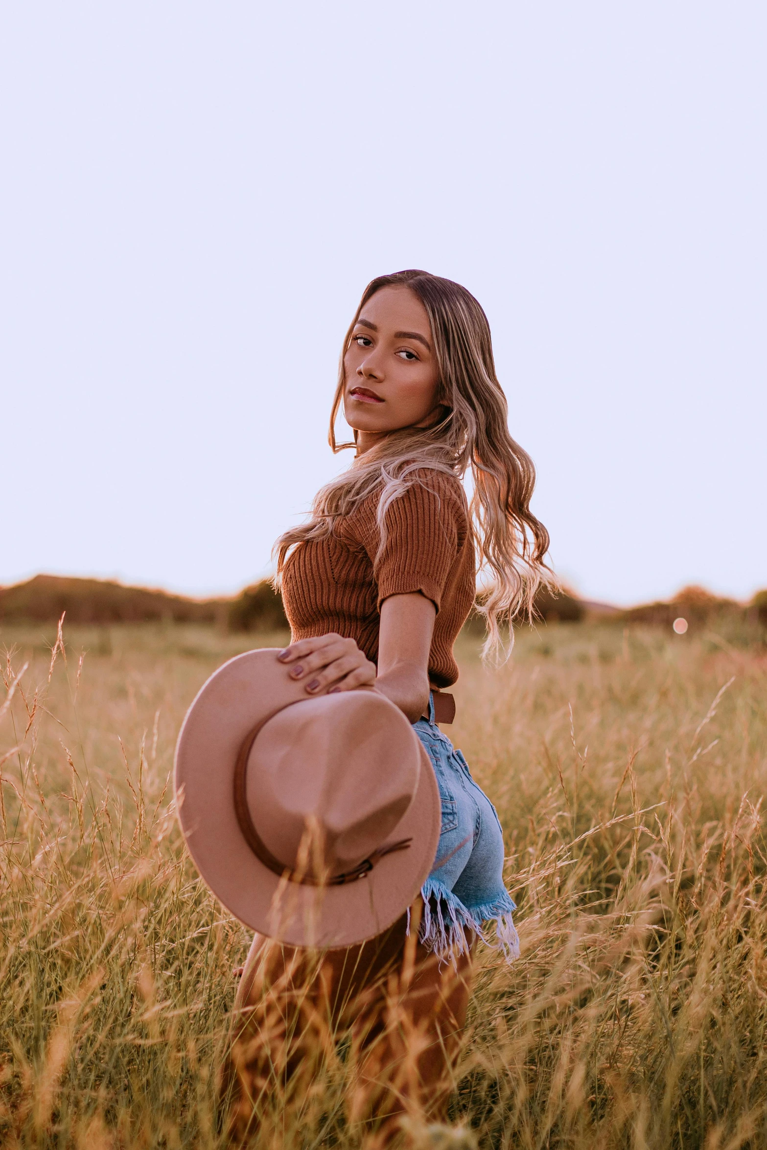 a little girl in an empty field with a hat on