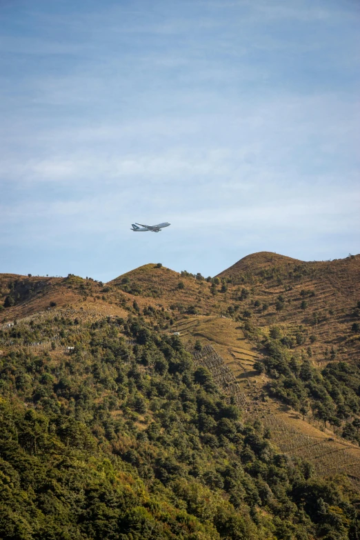 a airplane flying over the mountains with the sun coming down