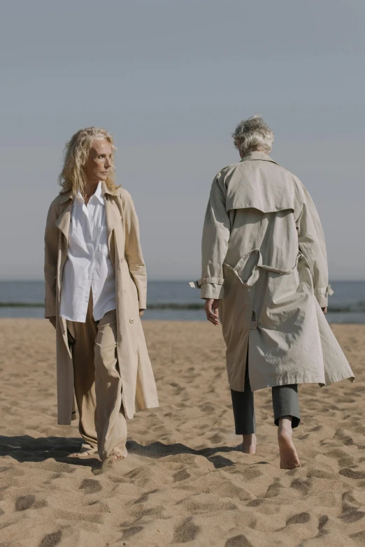 two women are walking down the beach with a man