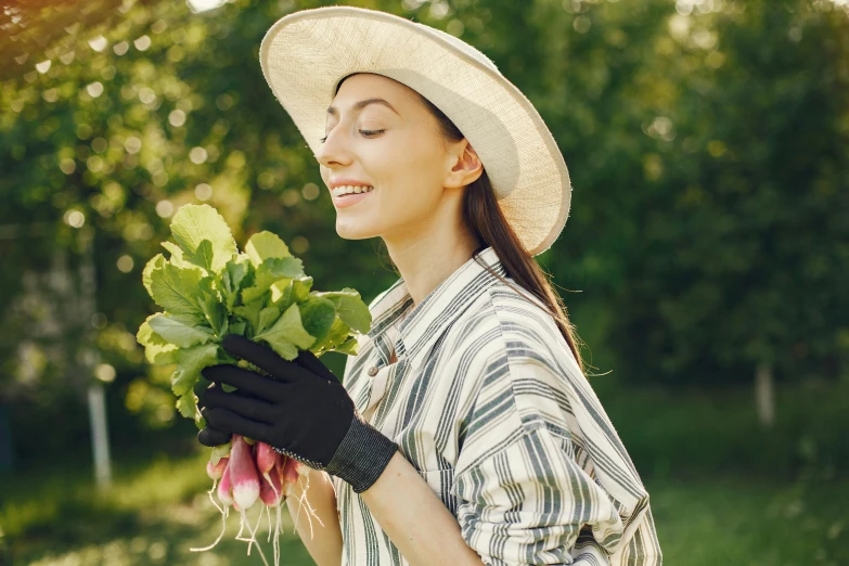 a girl in a hat holding out some greens