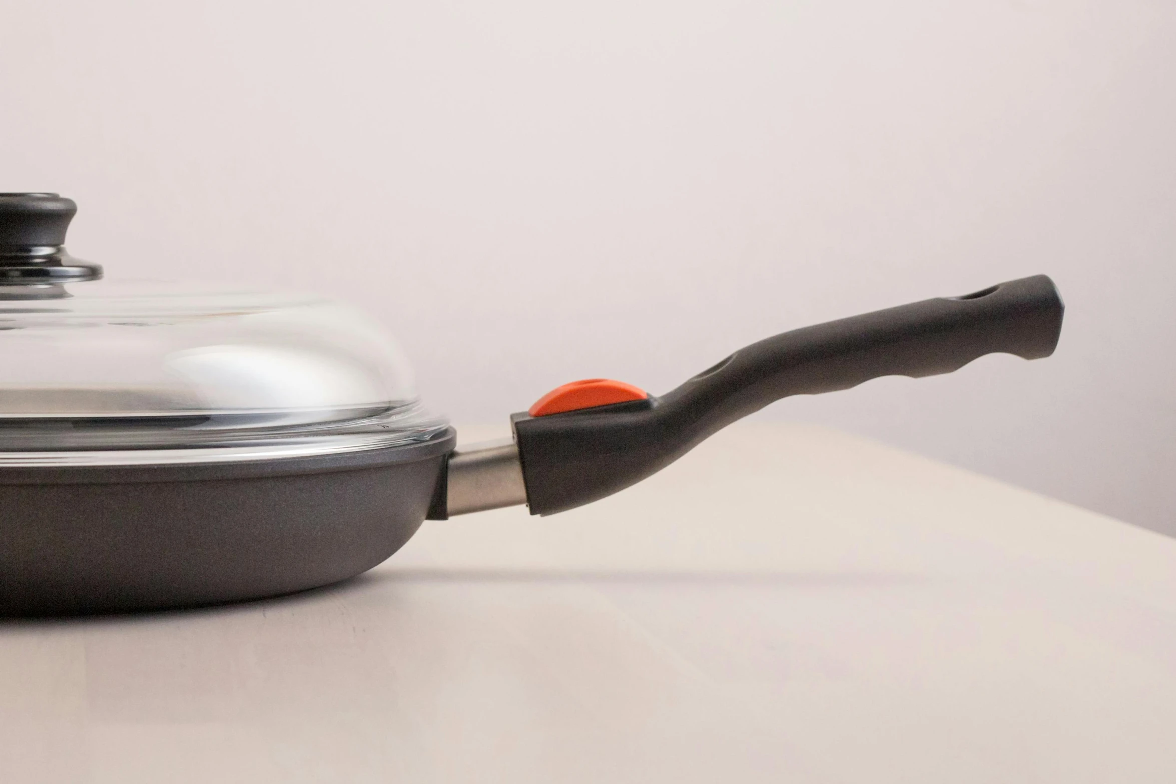 a saucepan with an orange handle is sitting on a counter