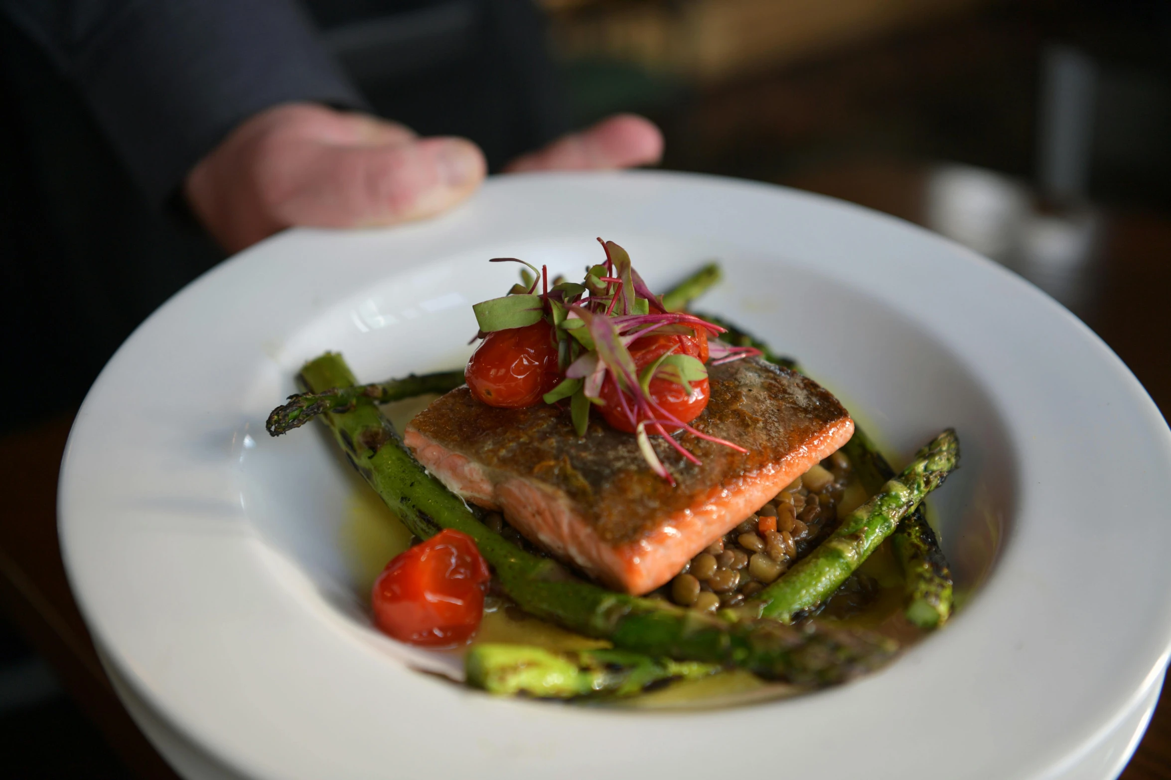 a white plate with vegetables and a piece of salmon