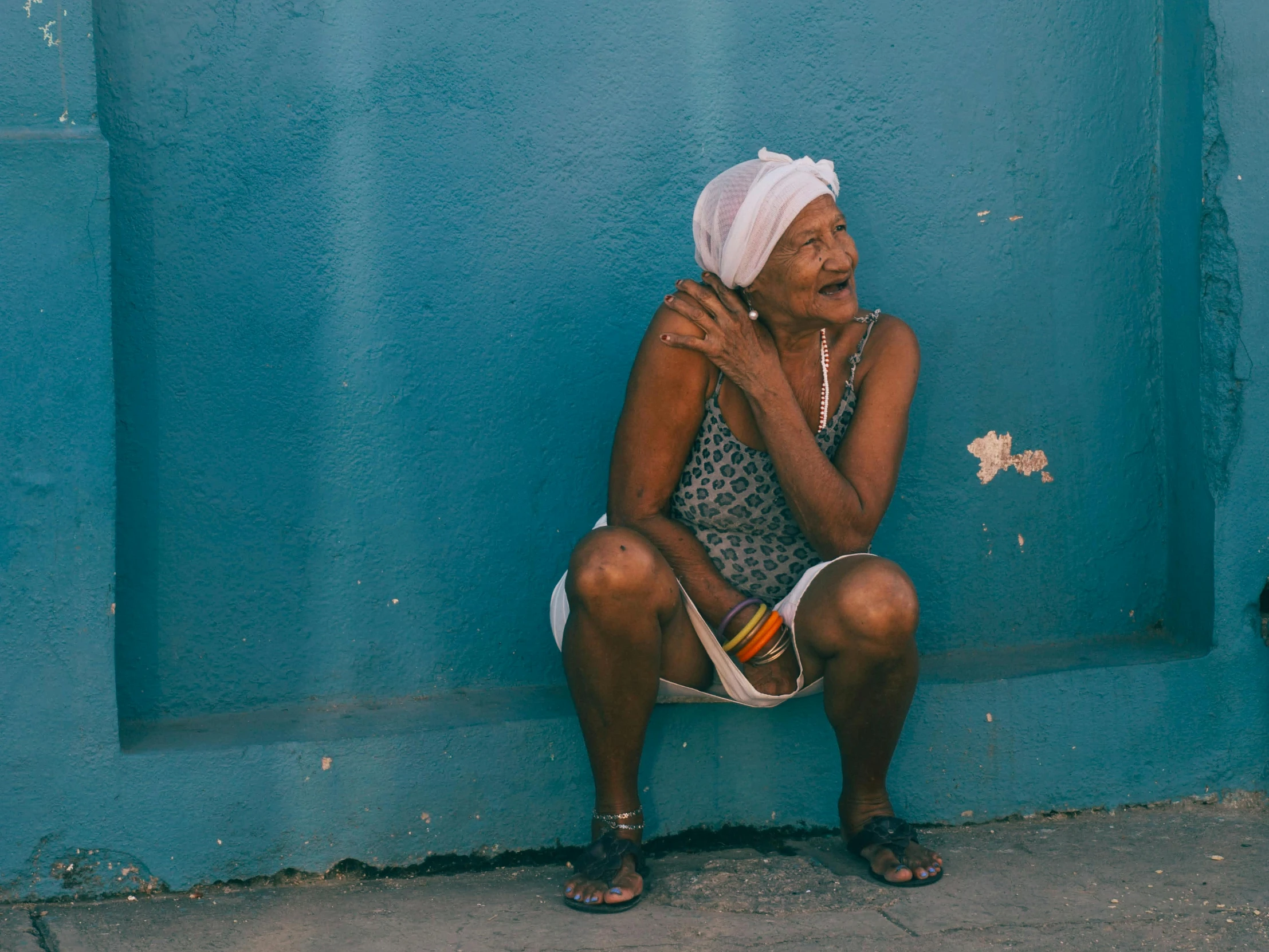 the woman is sitting against the wall in front of the building