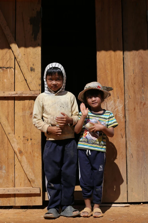 two small children standing together near a building