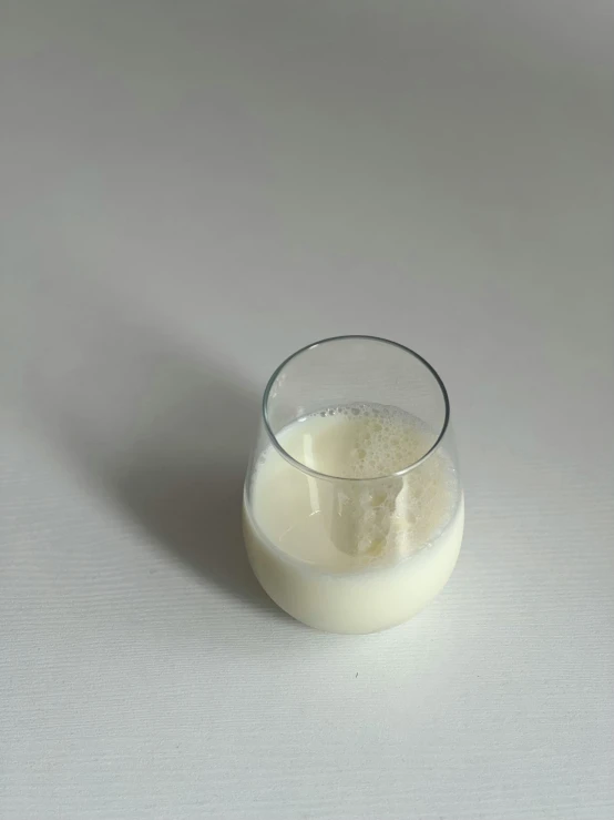 a glass full of milk on a white surface