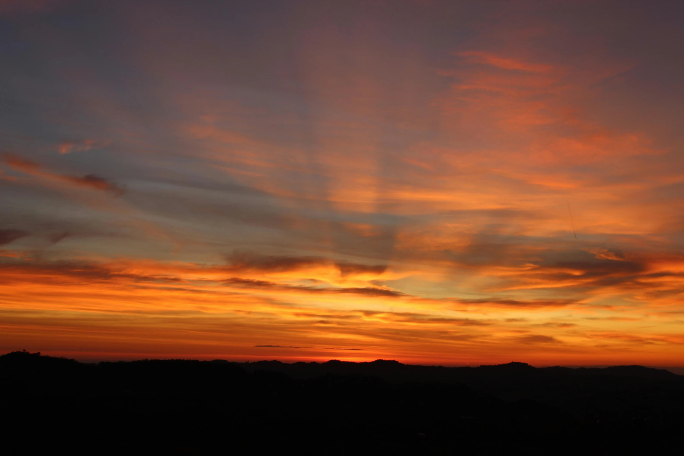 colorful sunsets and clouds above a mountain range