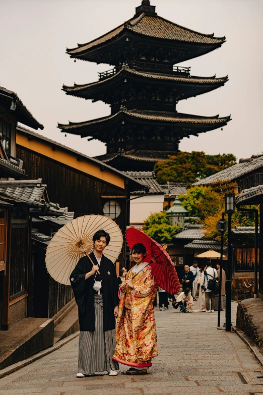 a young couple posing for a pograph together with the geisha standing behind them