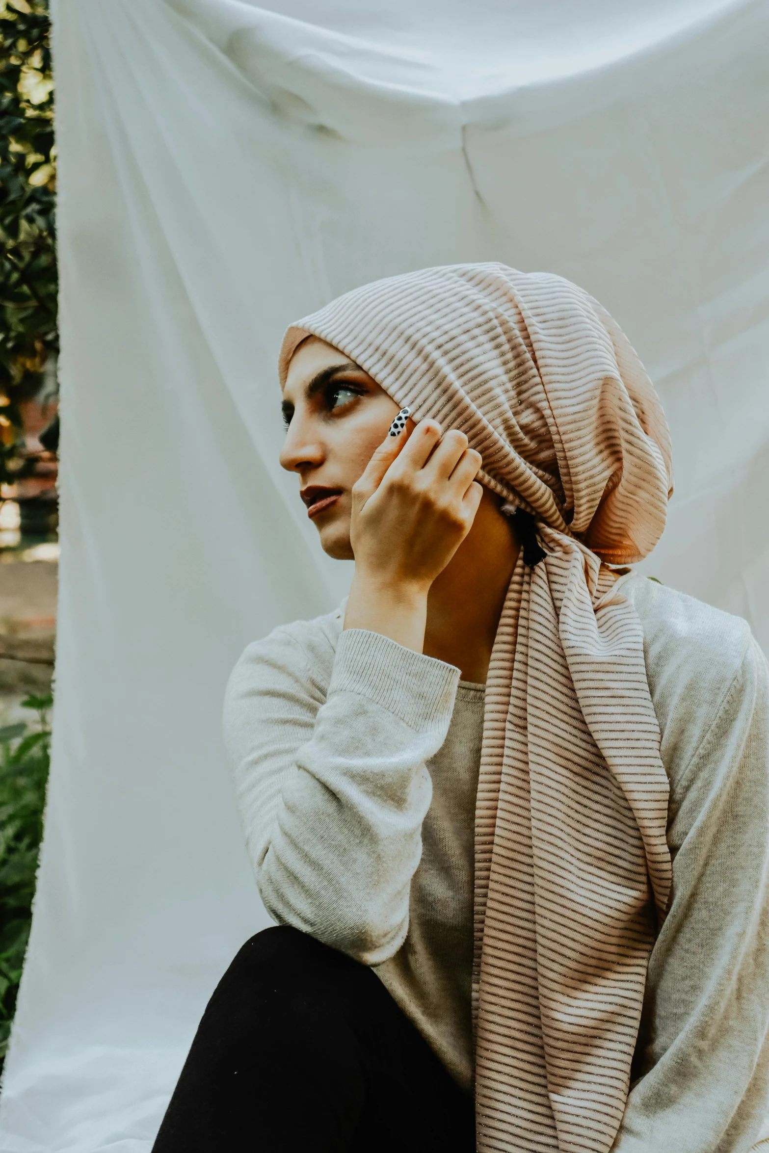 a woman in a scarf sitting against a white sheet